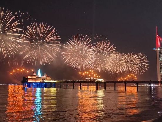 Fireworks over Dubai marina with Burj Al Arab in the background for New Year's Eve celebration.