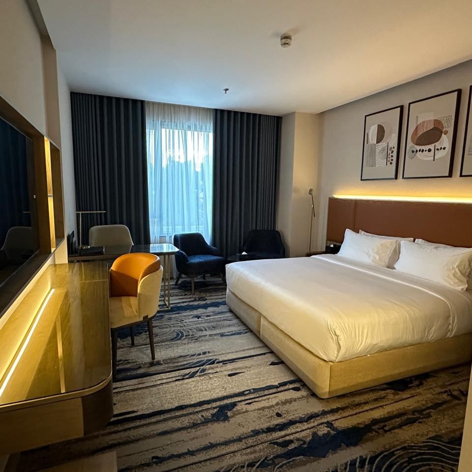 Elegant bedroom with large bed, chairs, desk, and modern decor at Jeddah Hotel & Spa