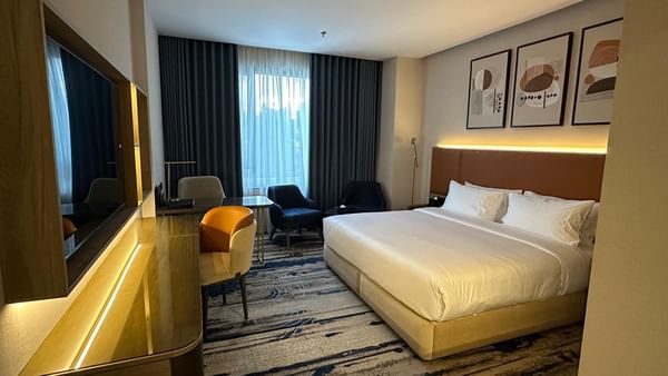 Elegant bedroom with large bed, chairs, desk, and modern decor at Jeddah Hotel & Spa.