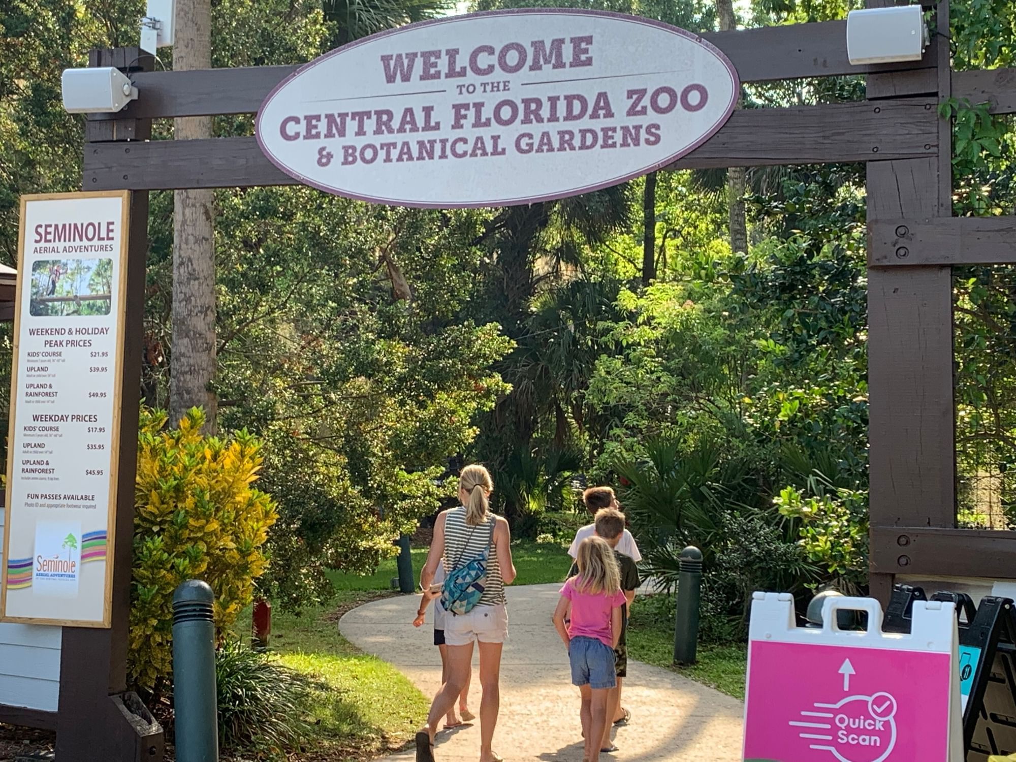 A woman and children enter walking beneath the entrance to the Central Florida Zoo.