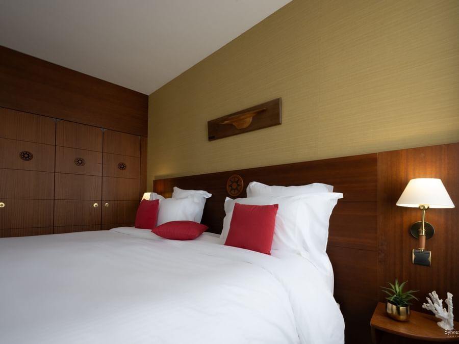 Chambre élégante avec lit double, décor maritime et lampe murale au Hôtel Le Yachtman.