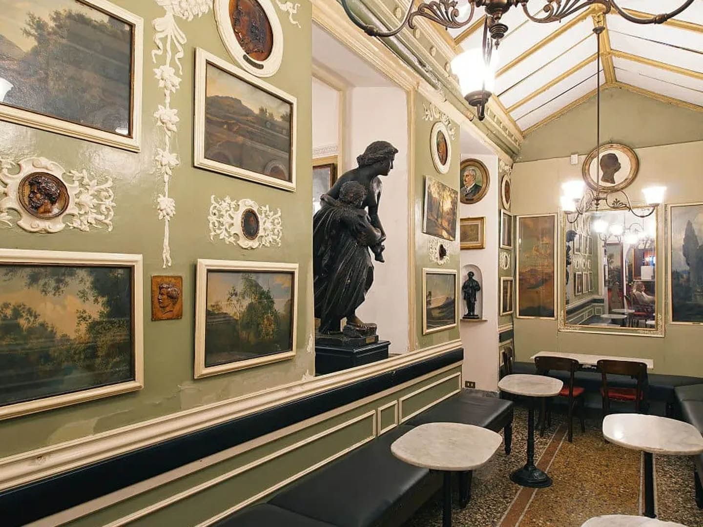 Elegant Antico Caffè Greco interior with vintage art, a striking statue, and dark seating near The Guardian Hotel
