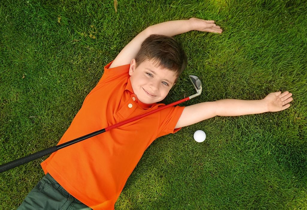 kid lying down with golf club and ball