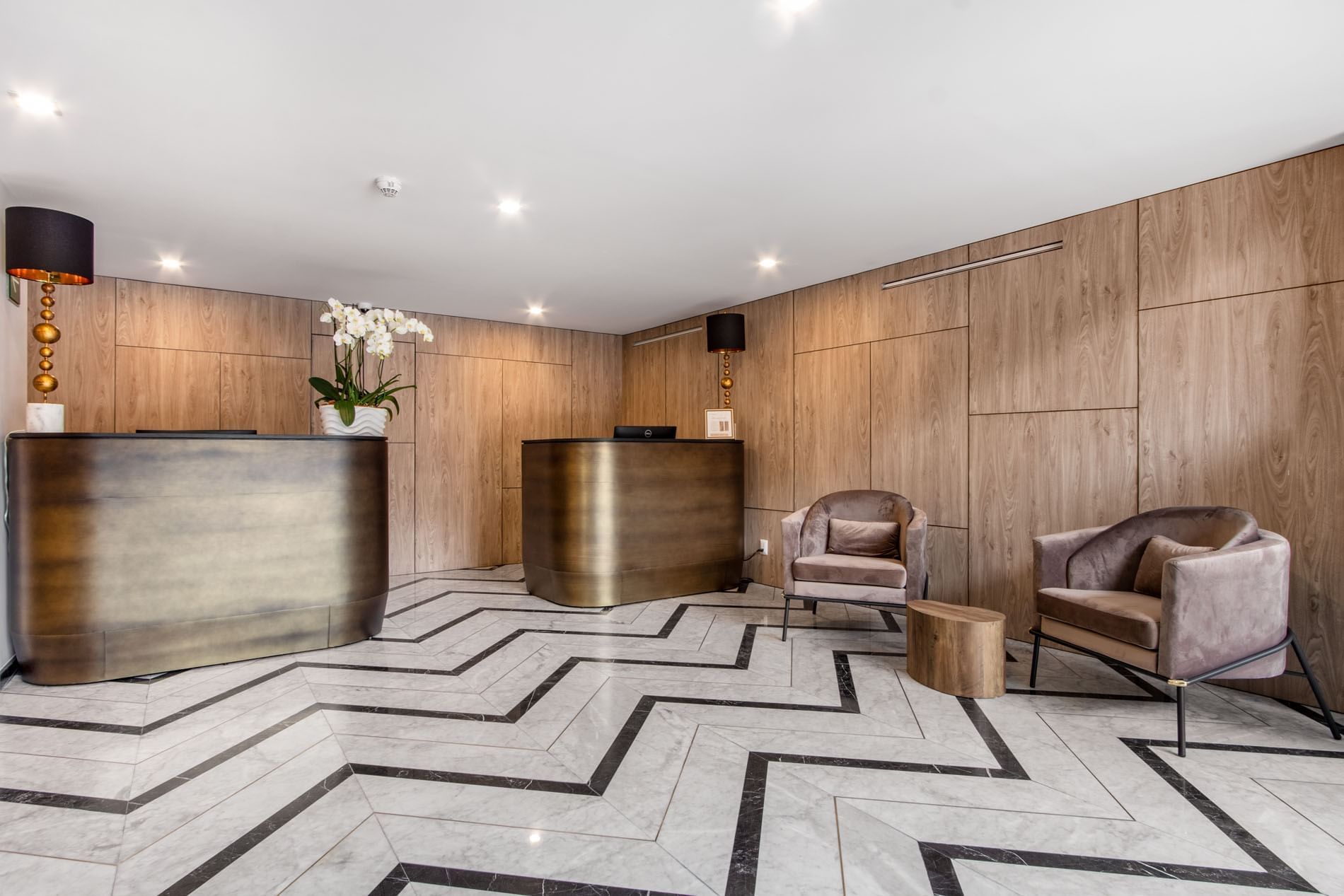 Sala de recepción con mostrador de bronce y sillas elegantes en hotel Elements by Marquis
