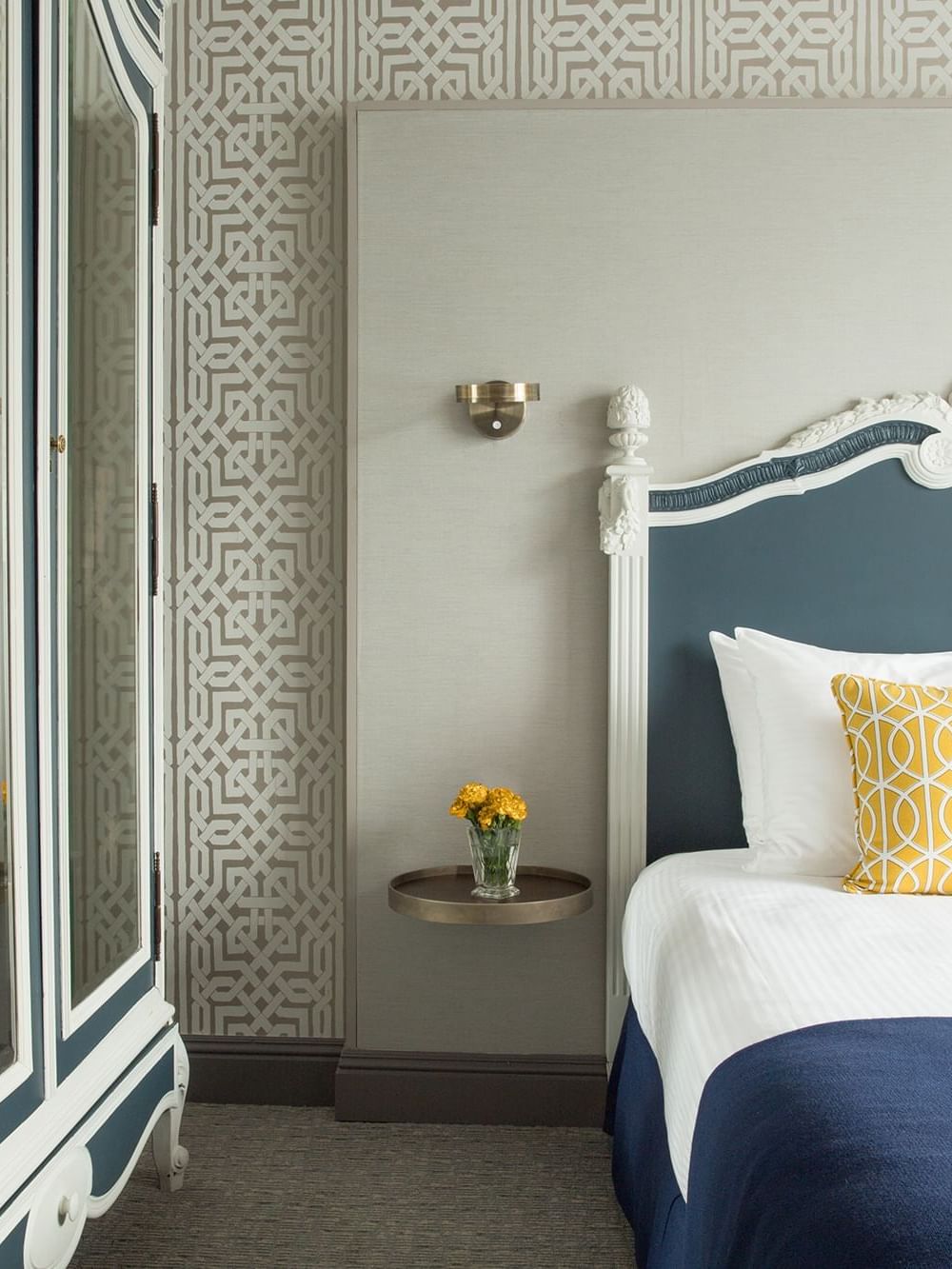 Deluxe Queen Room features Bed by a floating metal nightstand under a brass wall sconce at Warwick San Francisco