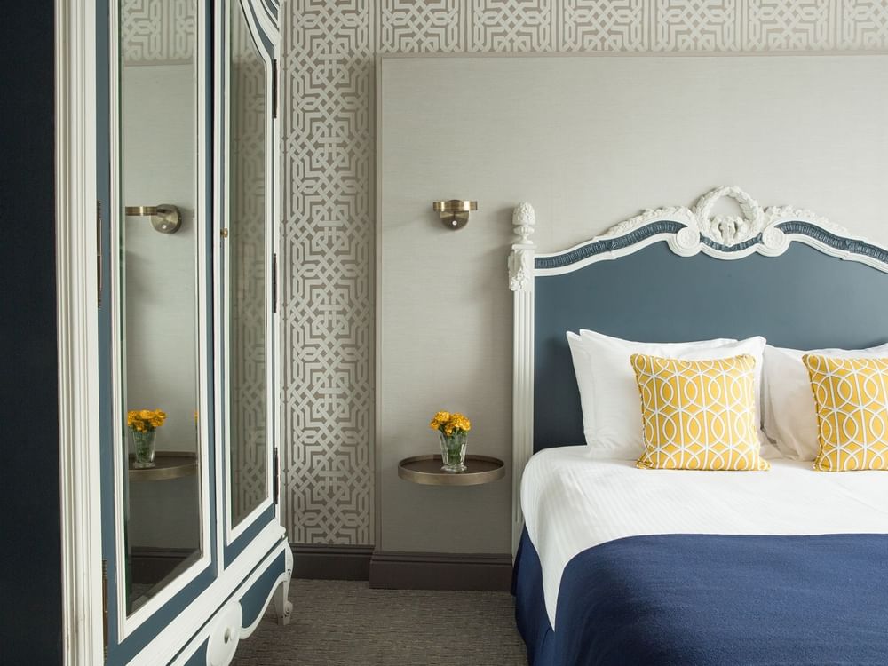 Deluxe Queen Room features Bed by a floating metal nightstand under a brass wall sconce at Warwick San Francisco