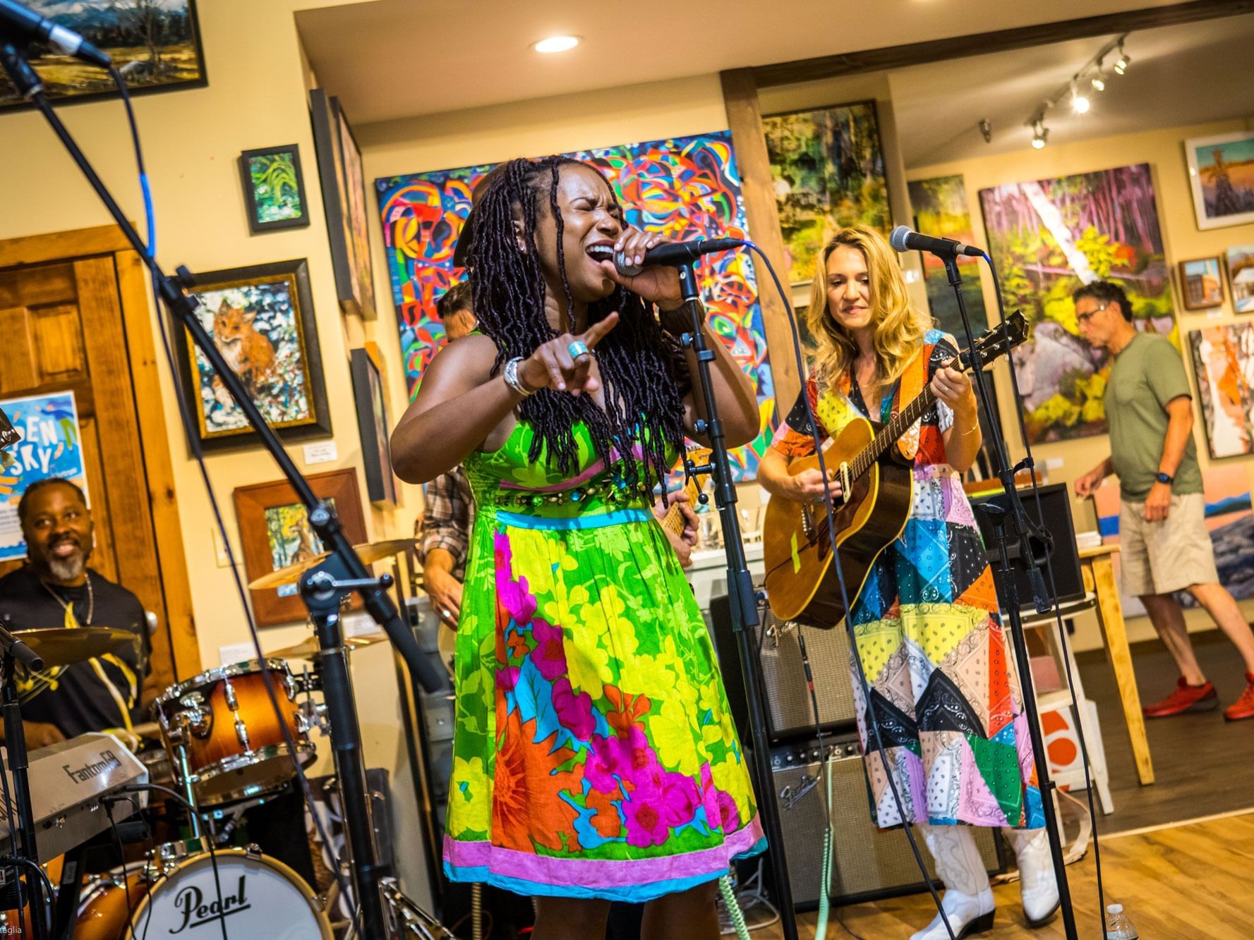 Live music performance featuring a singer and guitarist with a vibrant gallery backdrop at High Peaks Resort