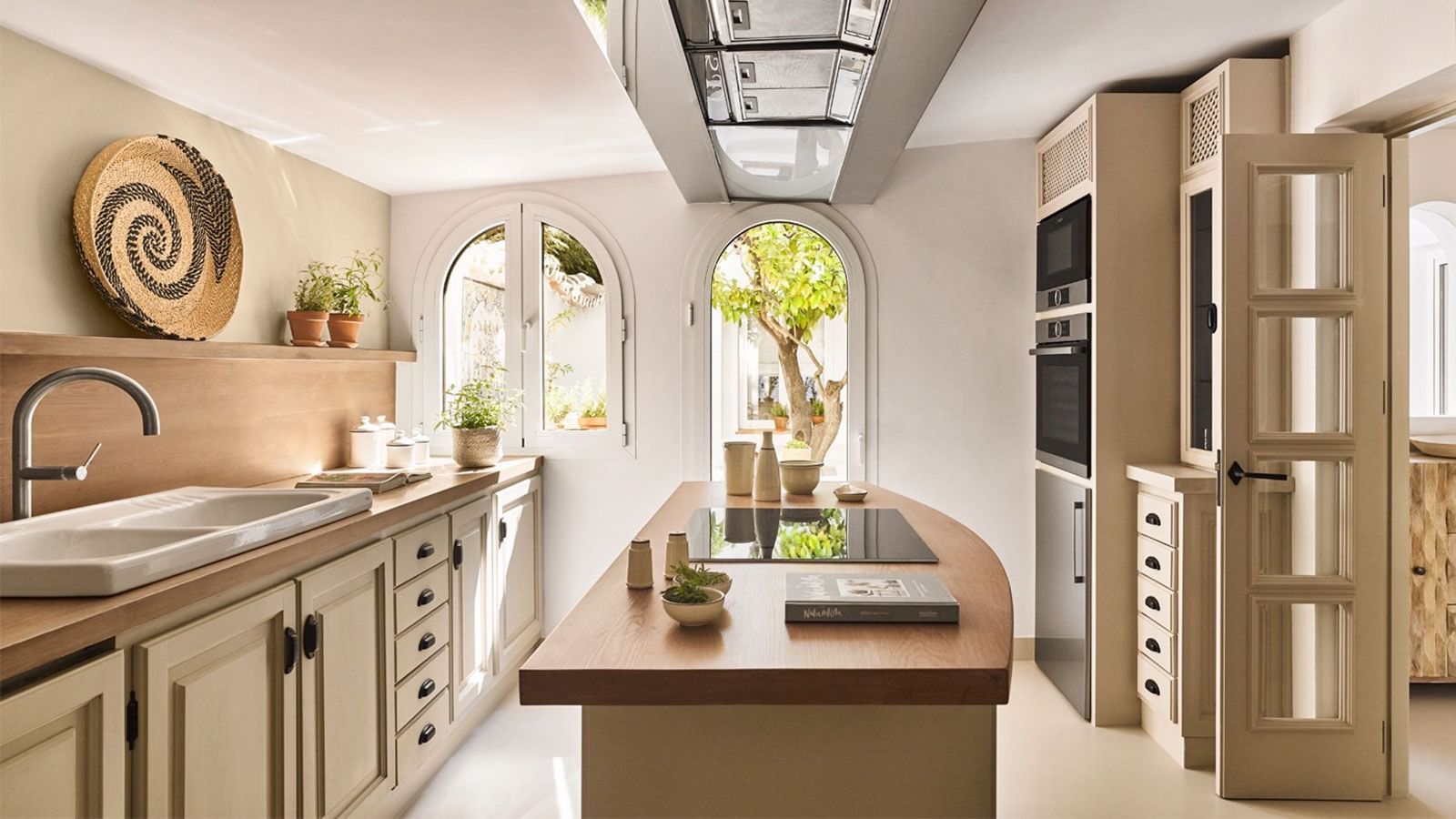 Wooden island placed between arched windows and tall white cabinets in Casabel at Marbella Club