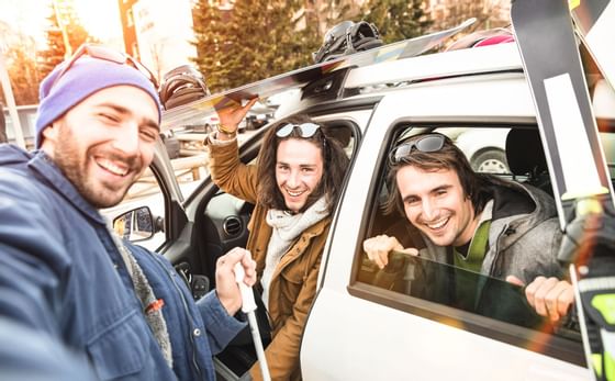 Three friends taking a selfie by a car near Blackcomb Springs Suites