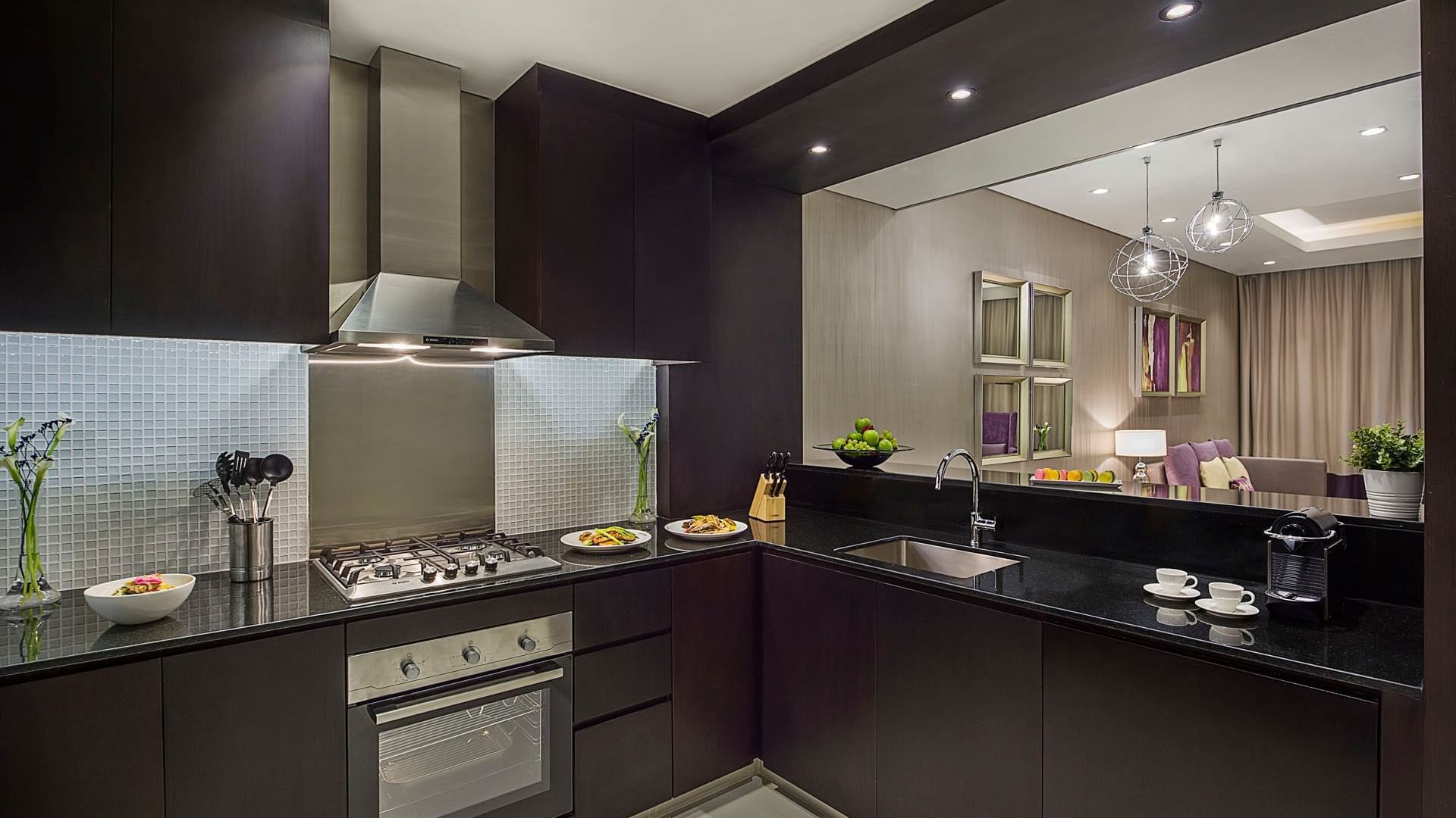 Kitchenette with black countertops and stainless steel appliances in Two Bedroom Suite at DAMAC Maison Distinction