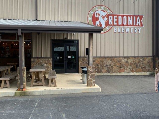 Entrance view of Fredonia Brewery with wooden dining tables and benches near The Fredonia Hotel