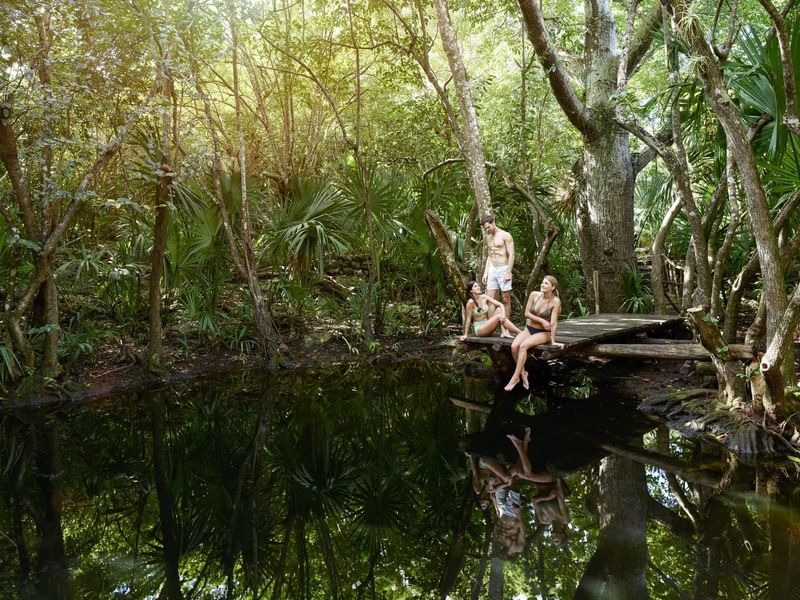 Friends lounging on a deck by a lagoon near The Explorean Resorts