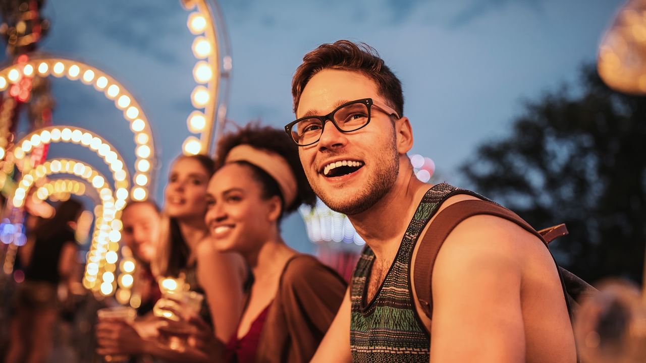 Smiling visitors enjoying a summer evening at an illuminated night fair