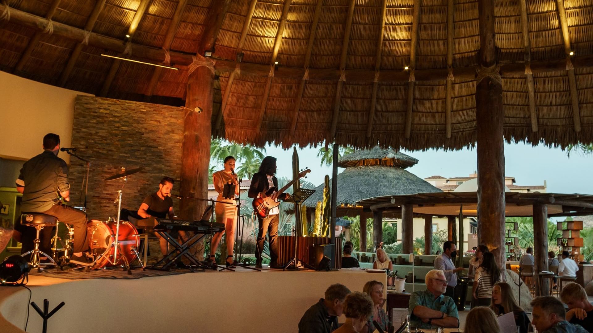 Banda musical en vivo en un escenario bajo techo de paja para los comensales en el restaurante Pitahayas de Hacienda del Mar Los Cabos