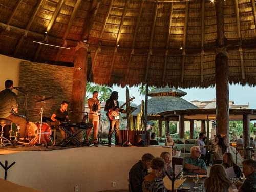 Banda musical en vivo en un escenario bajo techo de paja para los comensales en el restaurante Pitahayas de Hacienda del Mar Los Cabos