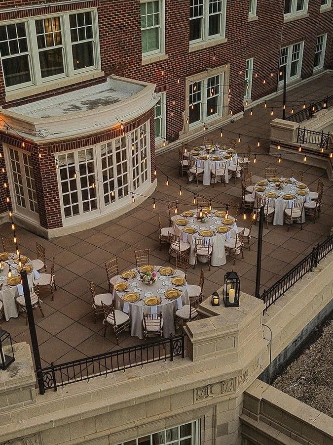 View of The Bridewell Suite with Round tables by string lights under a brick facade at Warwick Melrose Dallas
