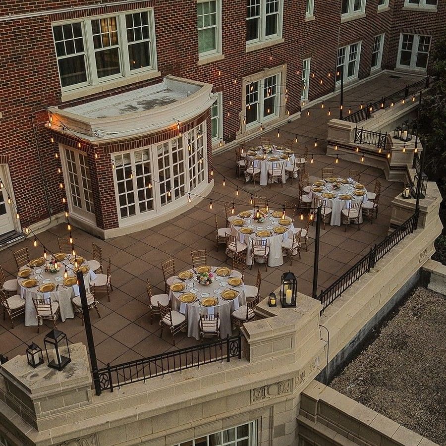 View of The Bridewell Suite with Round tables by string lights under a brick facade at Warwick Melrose Dallas
