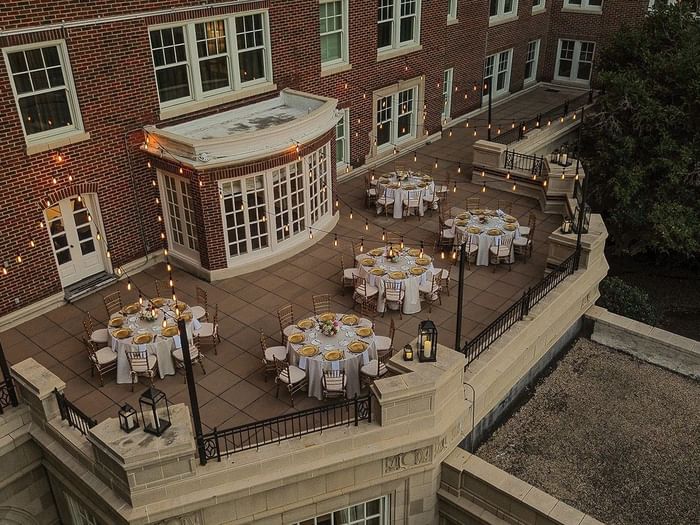 View of The Bridewell Suite with Round tables by string lights under a brick facade at Warwick Melrose Dallas