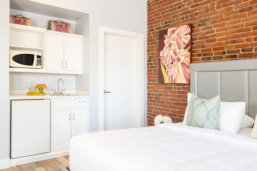 Kitchenette with pantry & appliances, king bed & brick wall in Premiere Loft Town & Country at Retro Suites Hotel