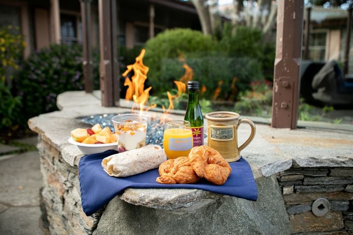 Breakfast wrap and croissants by a mug under a warm flame, surrounded by a blue napkin on a stone at Sea Otter Inn