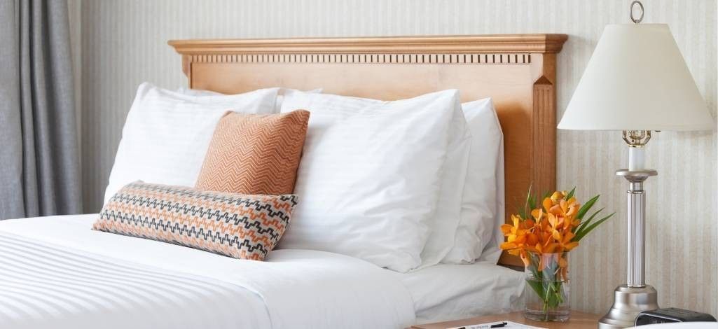 Hotel bed with pillows, lamp, and flowers