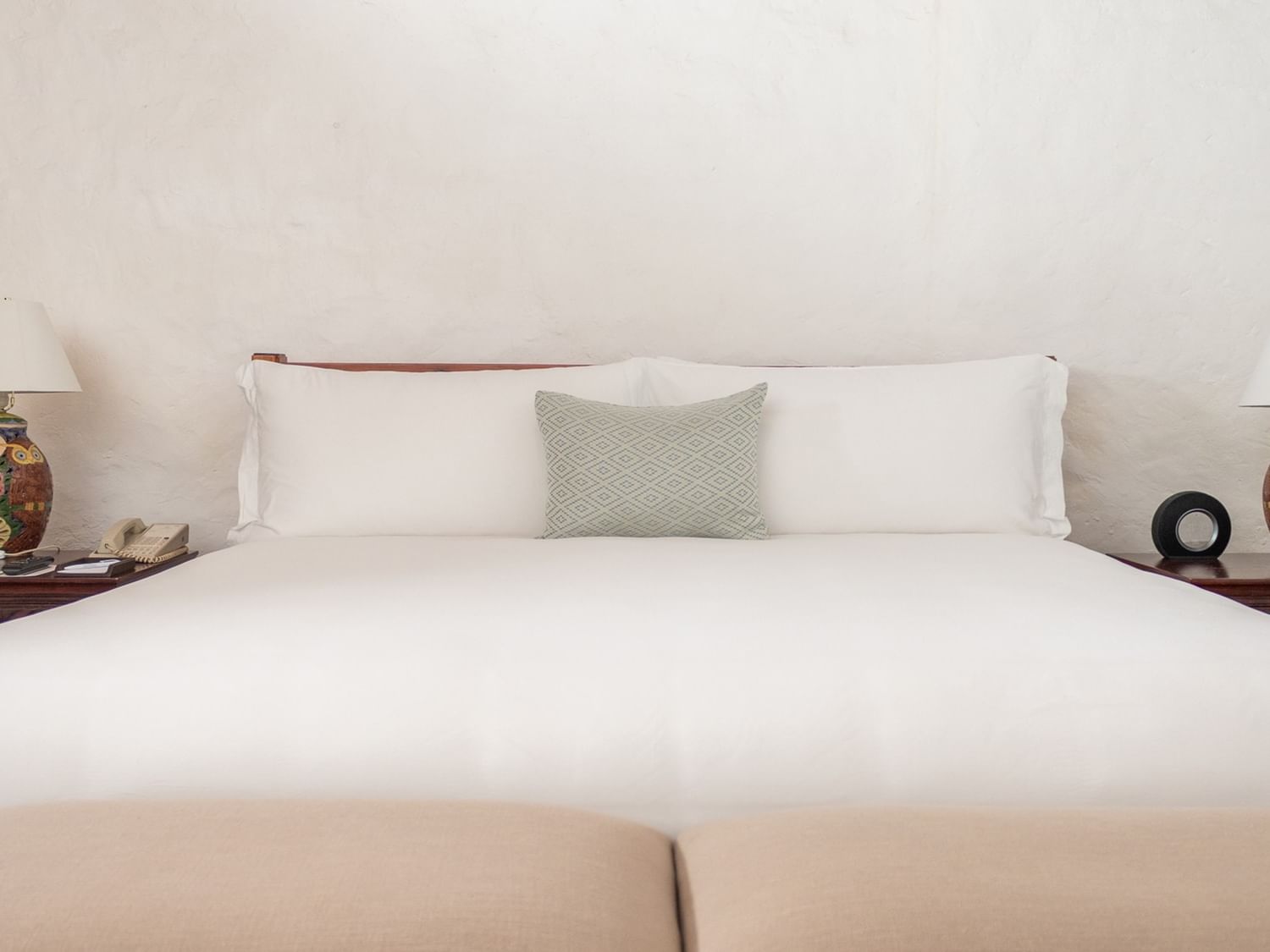White bed with a pillow and two lamps on nightstands at Quinta Real Oaxaca, Oaxaca de Juarez.