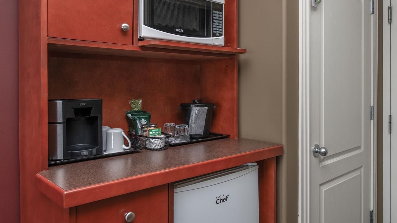 Compact kitchenette with cherry wood cabinetry, microwave, coffee maker, and mini fridge at Coast Edson Hotel.