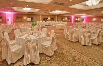 Grand ballroom set up with elegant white chair covers and round banquet tables for event at Clayton Plaza Hotel