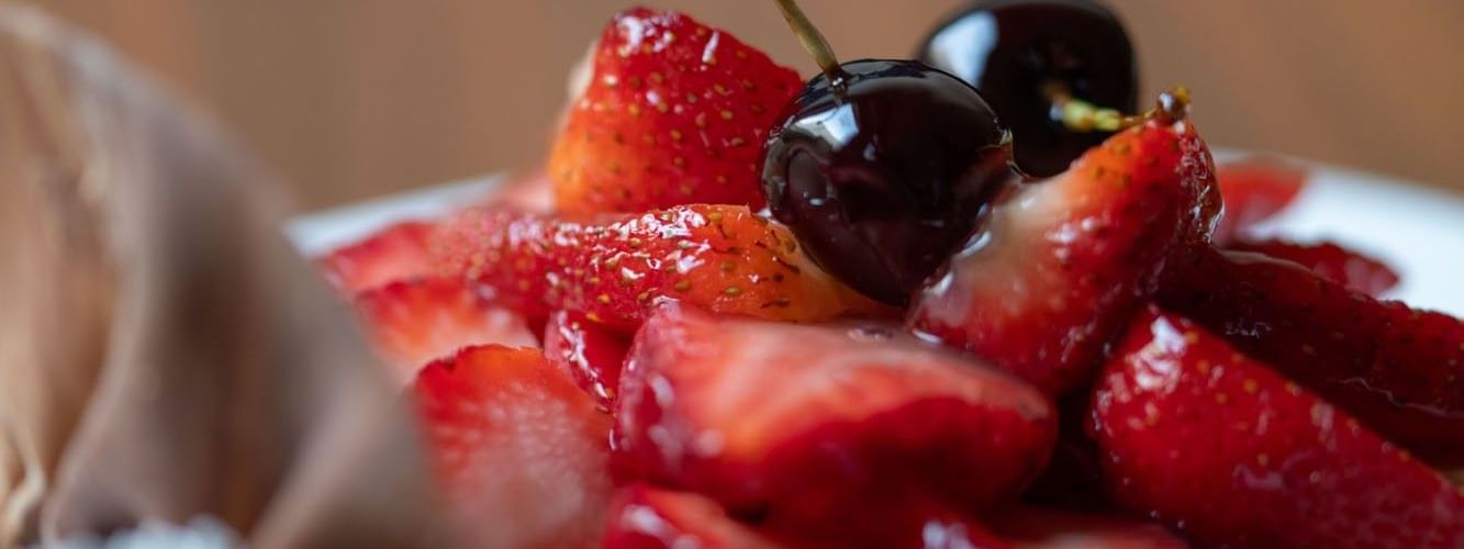 Close-up of a dessert tart topped with glossy sliced strawberries and cherries in Artist Lobby Lounge at Warwick Hotel Jeddah