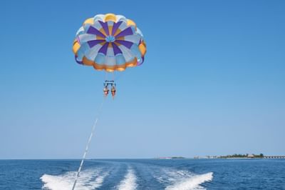 Two people parasailing over sea near Grand Park Kodhipparu