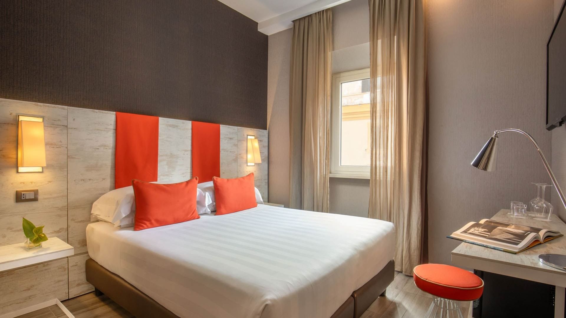 Modern Classic Room at The Guardian Hotel with a double bed, orange pillows, warm lighting, and stylish decor