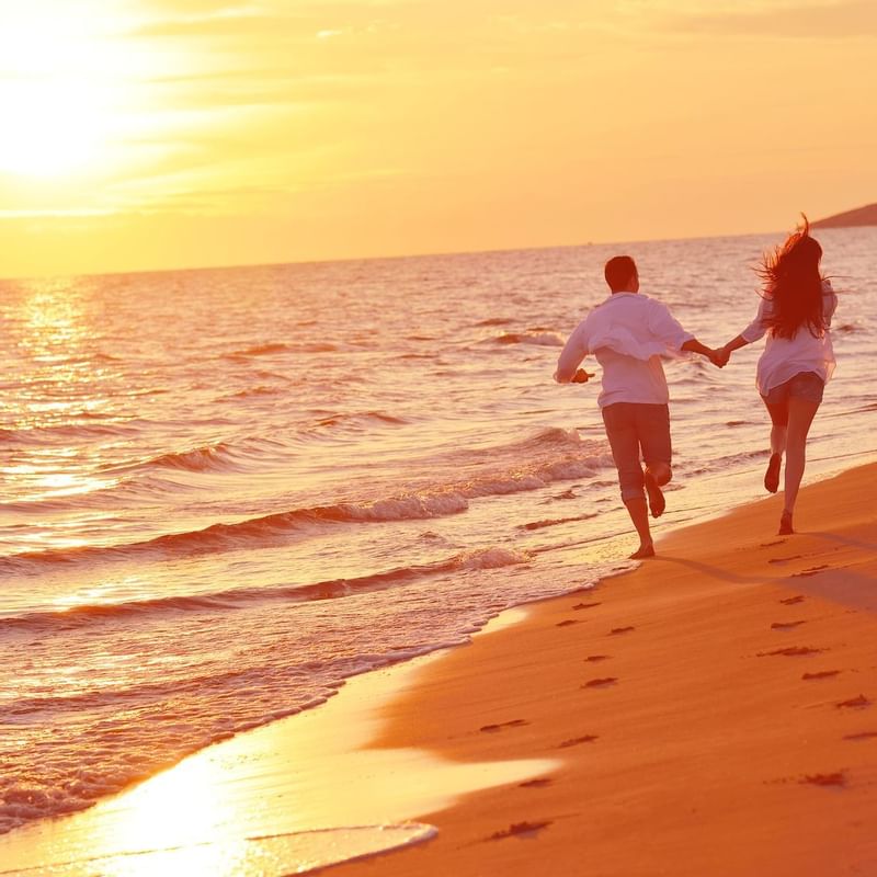 Couple holding hands & running on the beach at TokaToka Resort