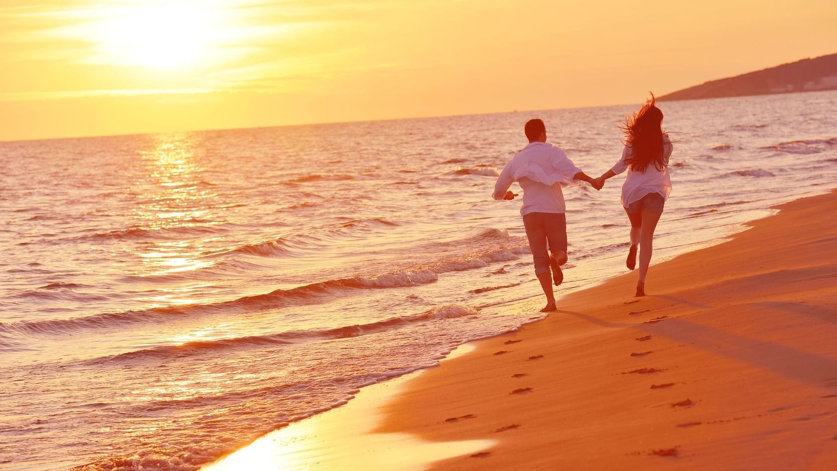 Couple holding hands & running on the beach at TokaToka Resort