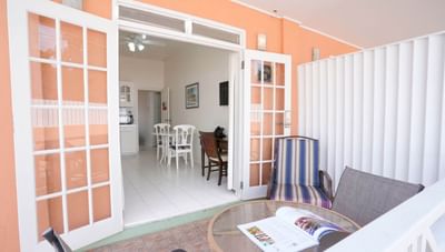 Patio table and chairs beside open double doors looking into a Junior One Bedroom living area at Worthing Court Apartment