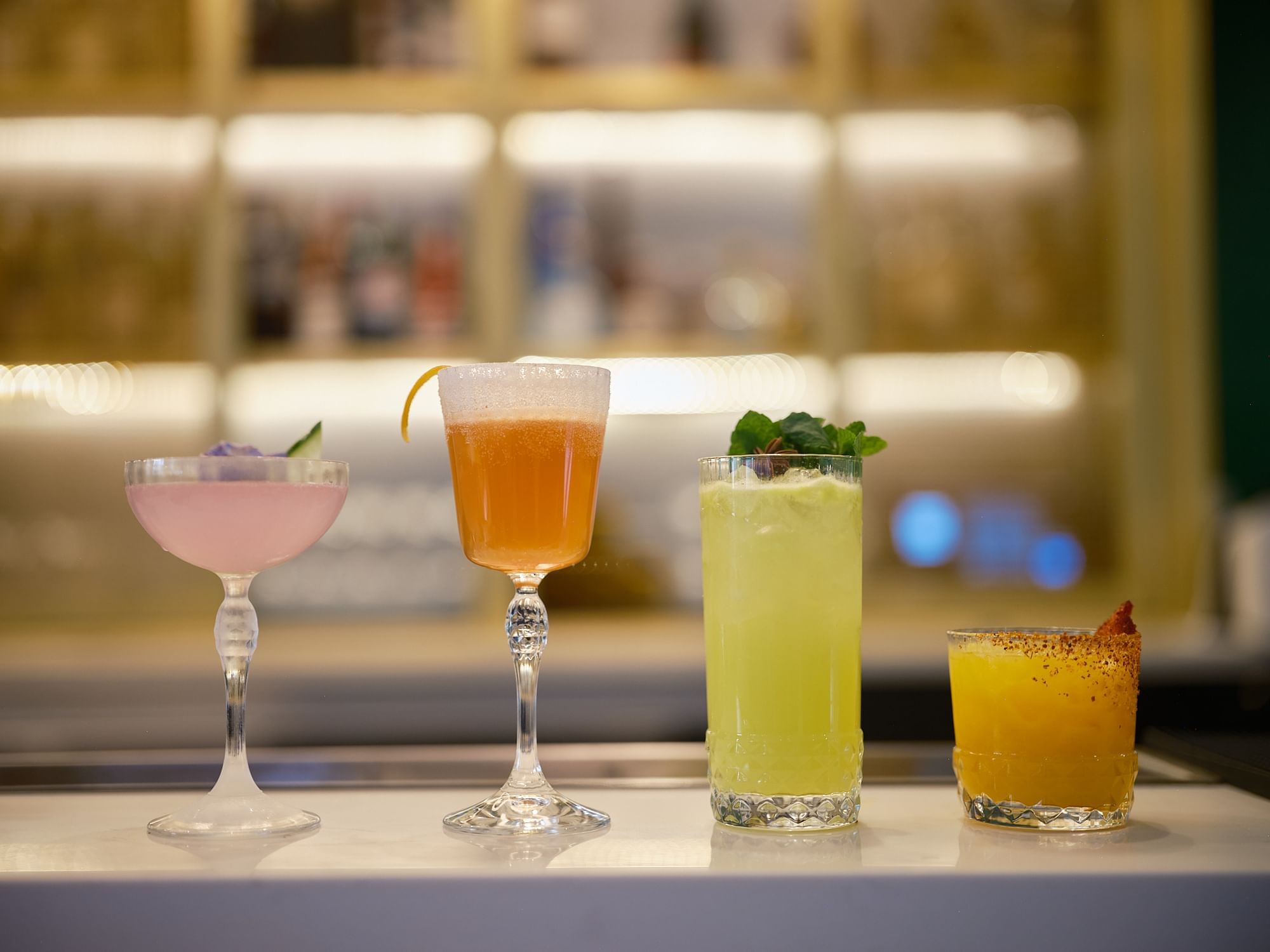 four cocktails on a bar