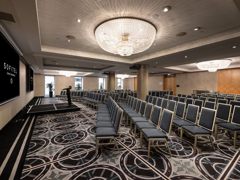 Brisbane room conference space with theater-style seating, crystal chandelier and presentation screen