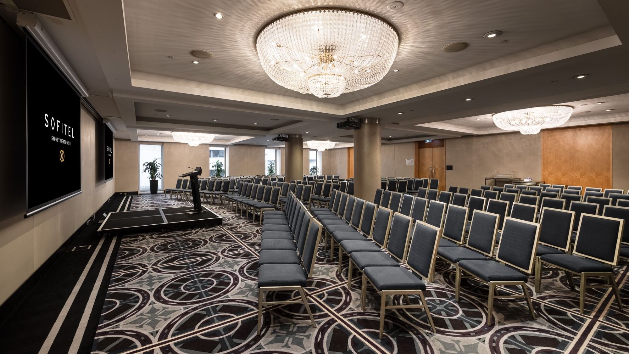 Brisbane room conference space with theater-style seating, crystal chandelier and presentation screen