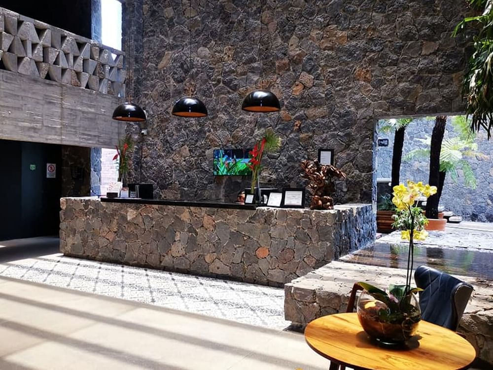 Reception front desk with a rock texture & lounge area at Huayacán Cuernavaca Curamoria Collection