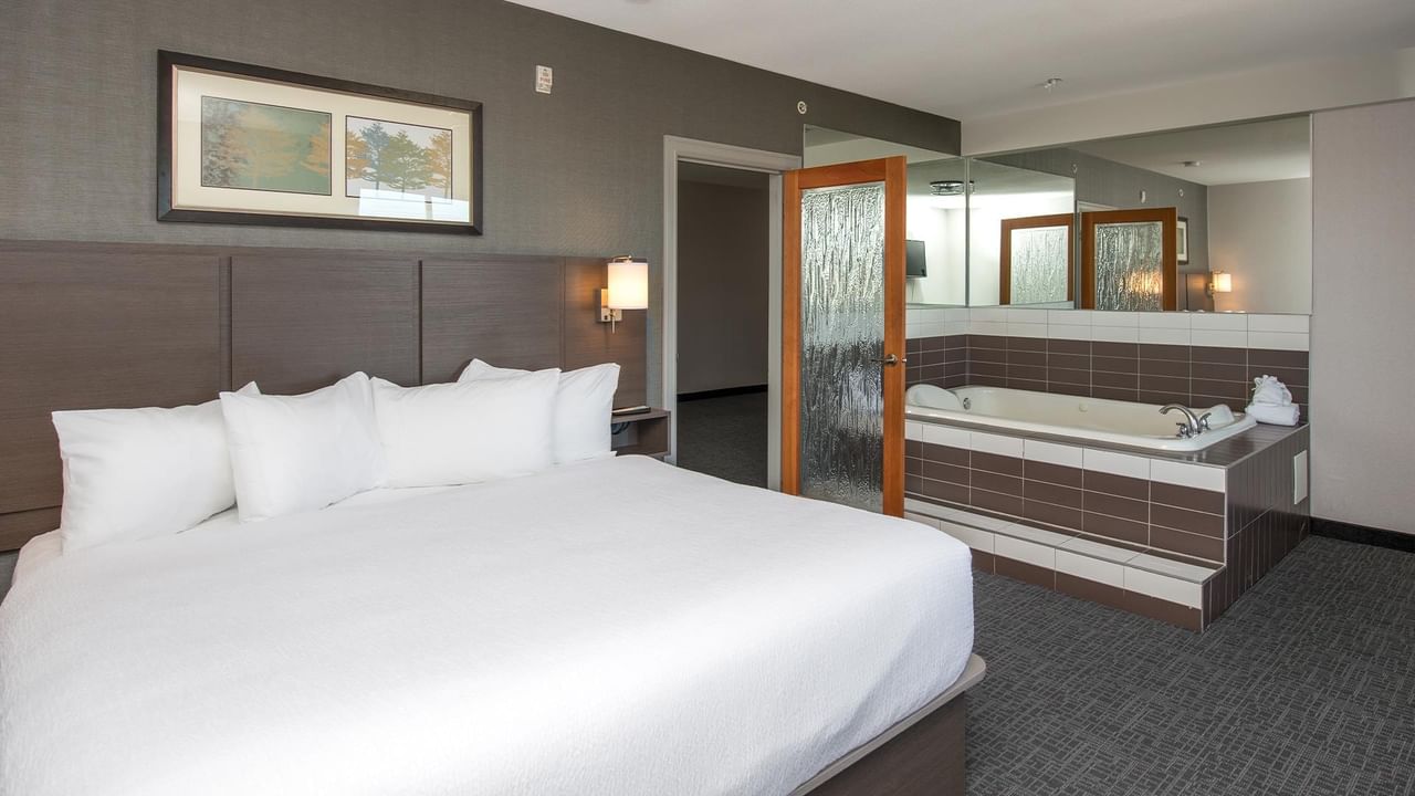 King-sized bed in a modern room with jetted tub.