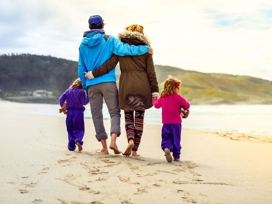 Family is walking on sandy beach near Daydream Island Resort