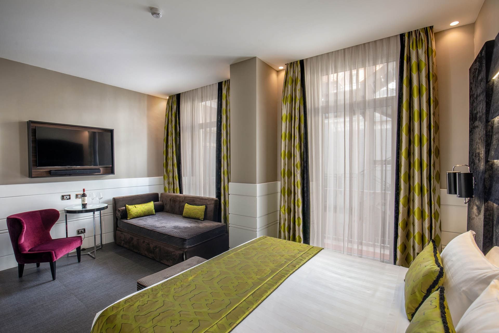 TV with seating facing the bed by the window in Deluxe Room at The Glam Hotel