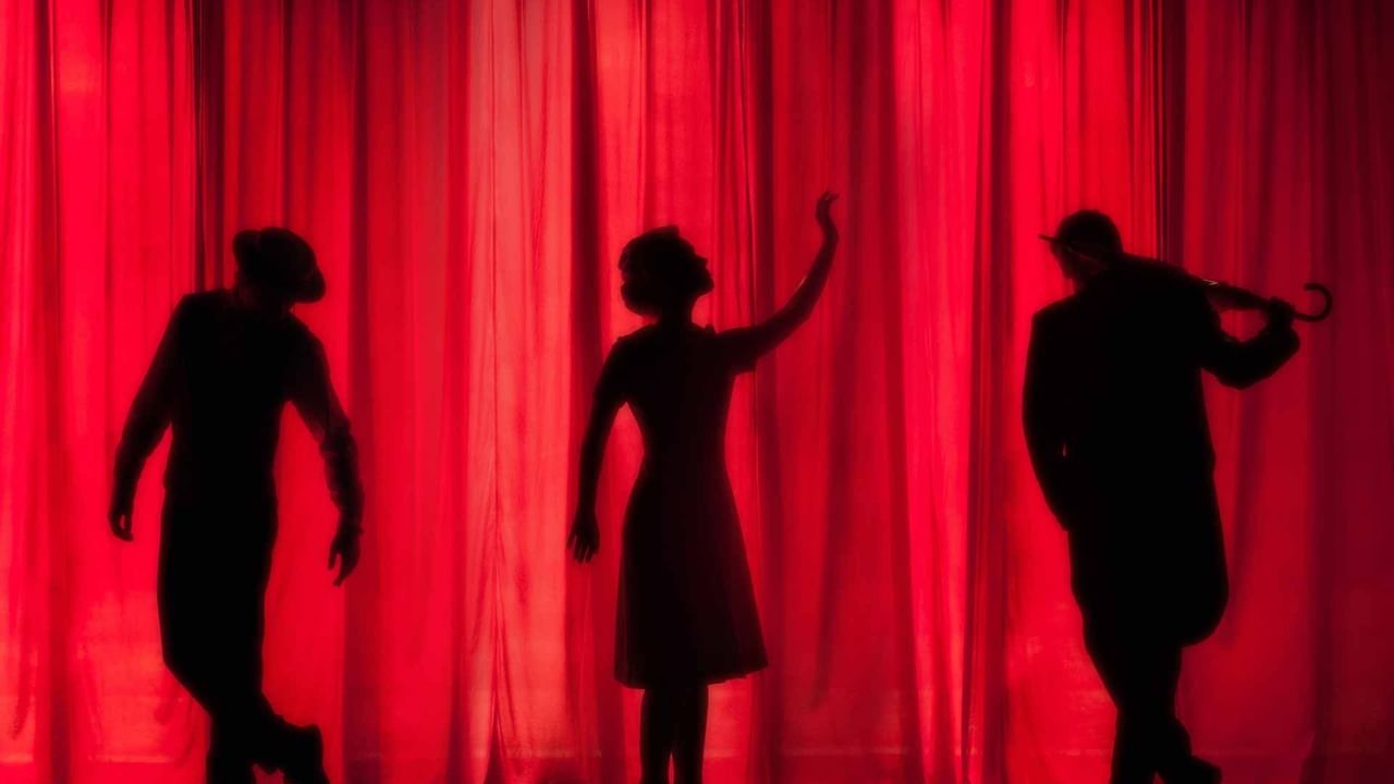 Silhouette of a performers in front of a red curtain