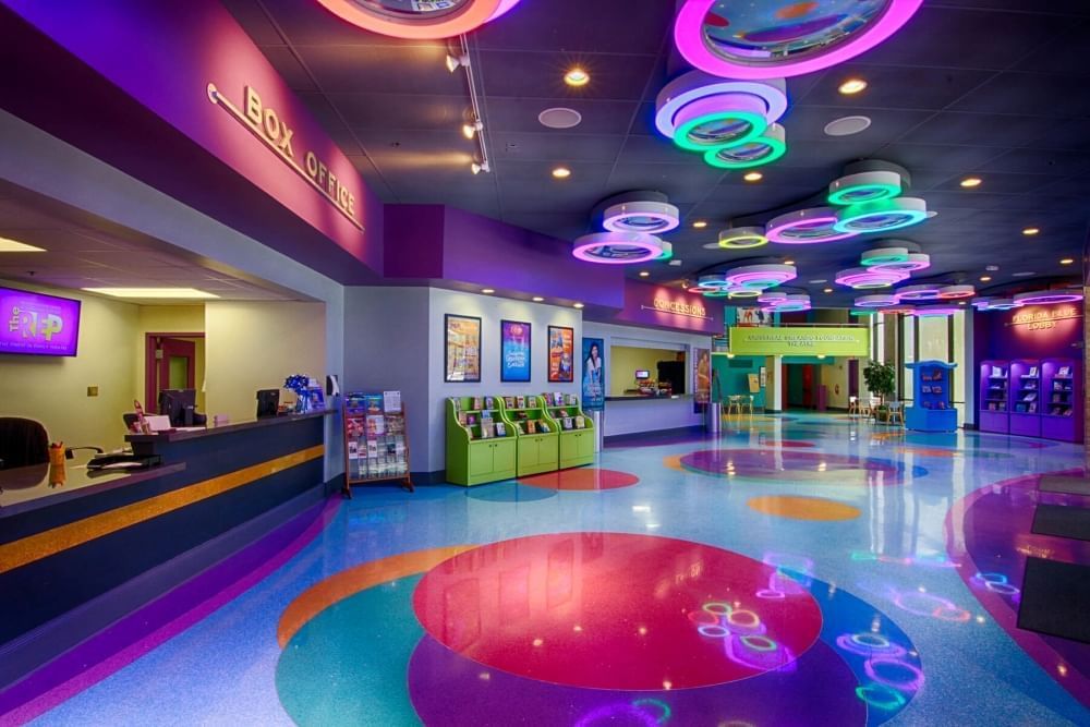 A colorful lobby with circular LED lights in green and purple on the ceiling, and big red, purple, and yellow circles on the floor. Check out family-friendly entertainment in Orlando onstage at Orlando Family Stage. 