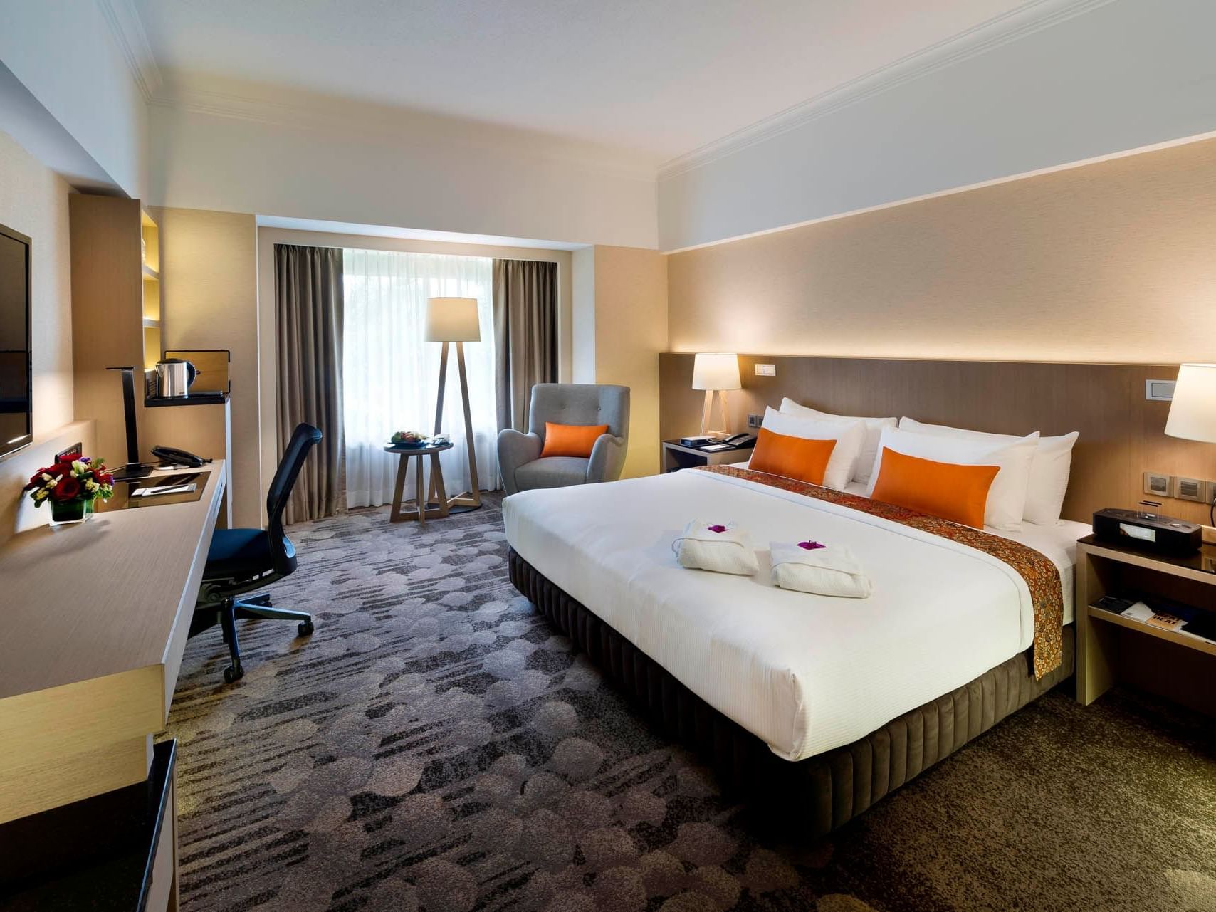 Modern Deluxe Room at The Saujana Hotel Kuala Lumpur with a king bed, work desk, armchair, and large windows