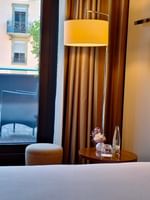 Round table by a bed under a floor lamp with chairs on a balcony in Deluxe Terrace Room at Warwick Geneva