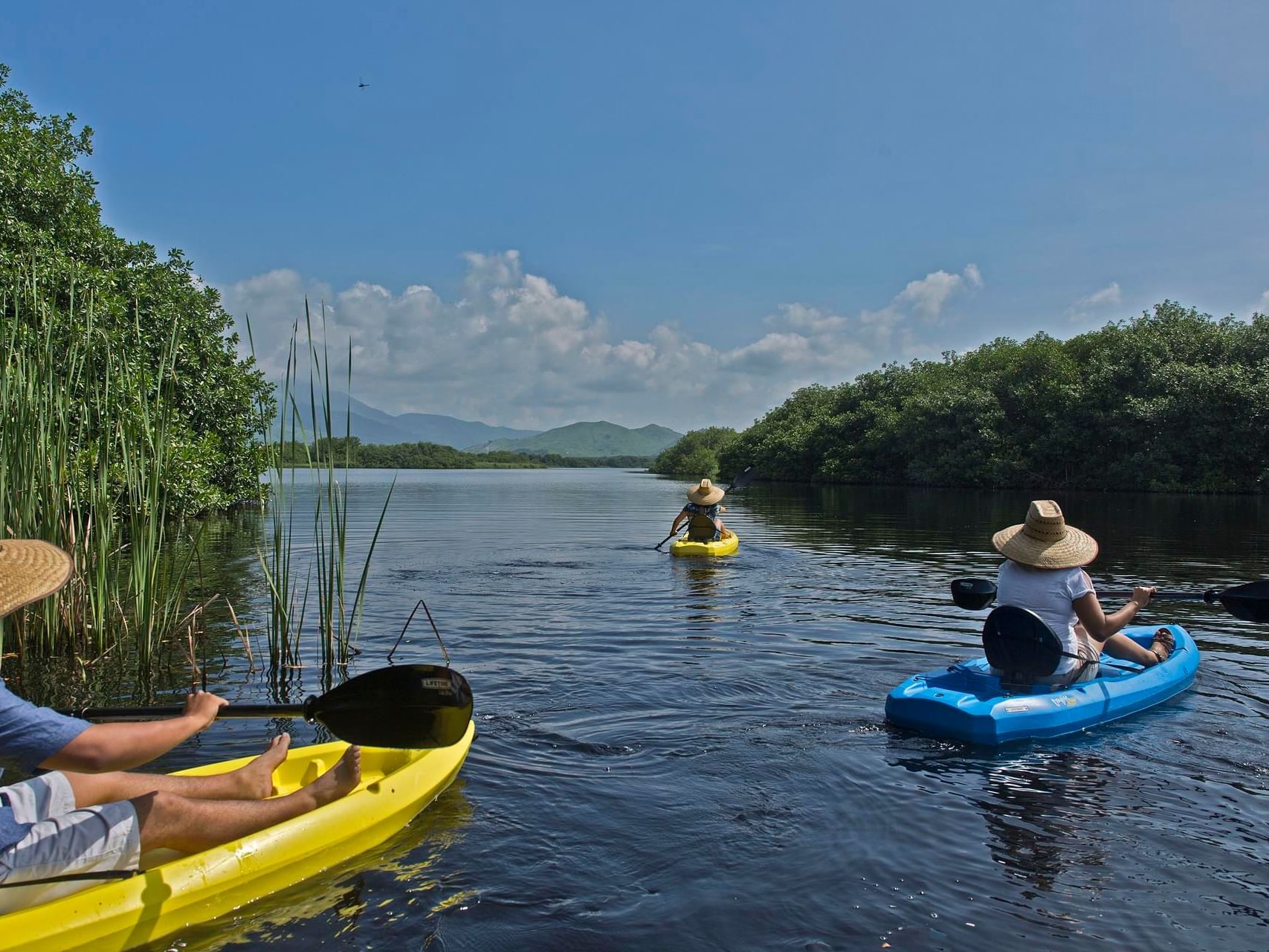 Three people kayaking on a river near Marea Beachfront Villas