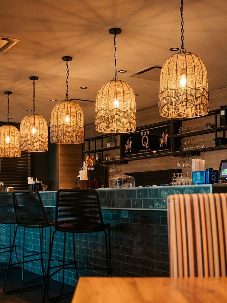 Sicilia interior with woven pendant lights, a blue countertop, and high stools at El Conquistador Resort