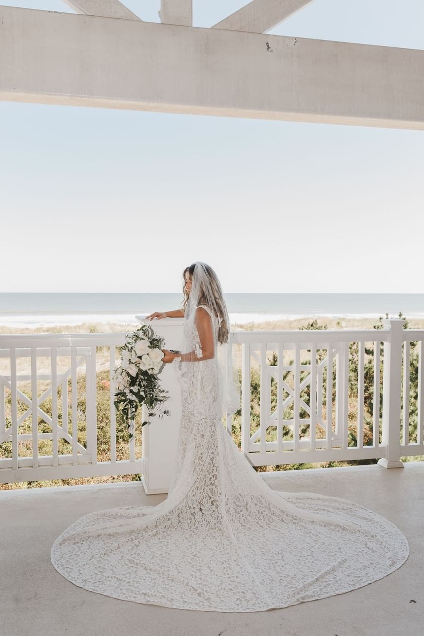 A bride holds her bouquet for a photo overlooking the ocean at our Avalon wedding venue