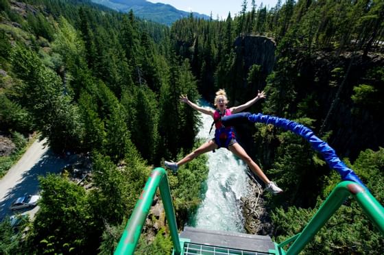 Woman bungee jumping off a rope bridge near Blackcomb Springs Suites