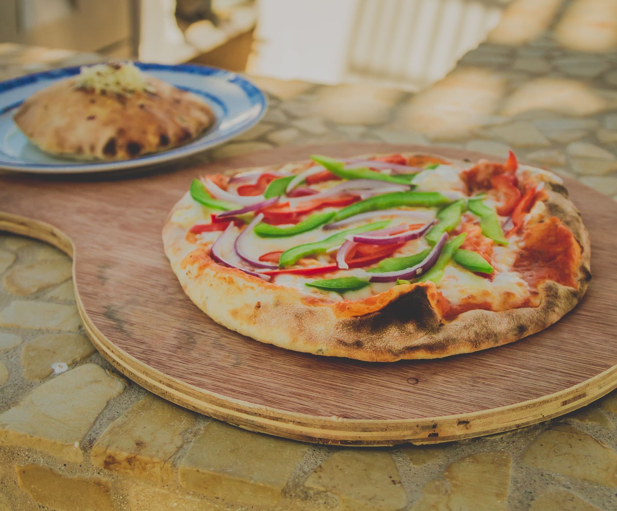 Closeup of a served pizza on an outdoor table at Los Cabos